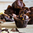 A rich dark chocolate injected chocolate tulip muffin with golden candied pieces in a brown paper casing