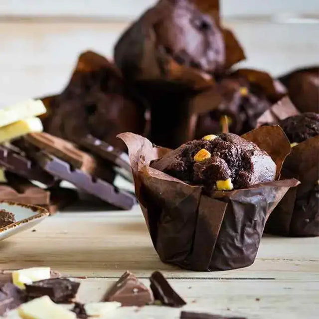 A rich dark chocolate injected chocolate tulip muffin with golden candied pieces in a brown paper casing