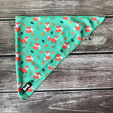 Teal inquisitive fox cooling bandana with playful orange foxes, green leaves, and lighter green stitching for dogs