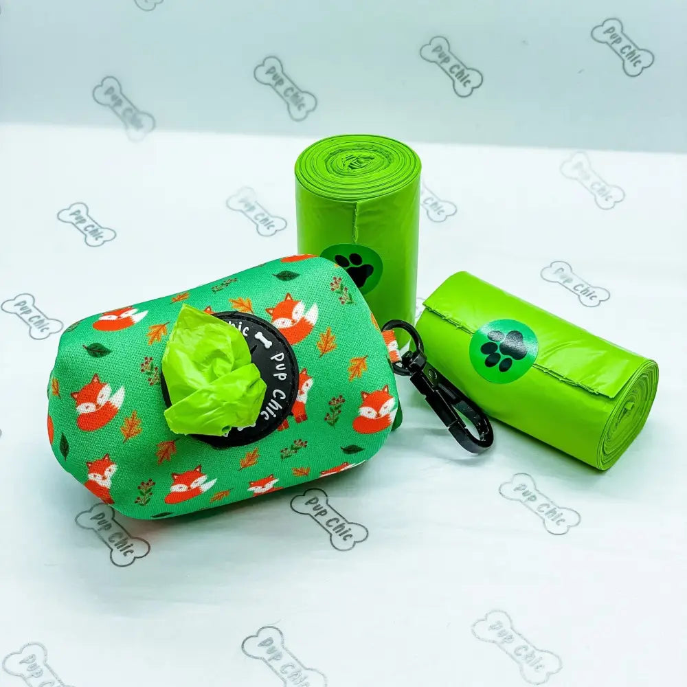 Green fabric inquisitive fox poo bag holder with fox leaf pattern black opening and carabiner clip for dog waste bags