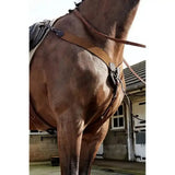 Brown leather horse saddle with black padding and metal hardware featuring the john whitaker ready ride elastic breastplate