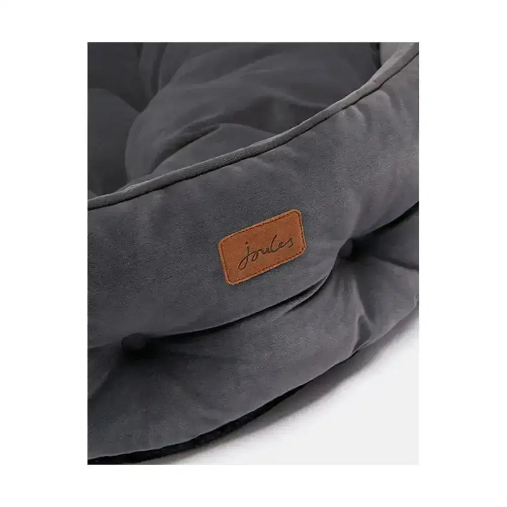 A plush dark grey joules chesterfield pet bed with soft suede texture and tan leather brand patch for sleeping dogs lie