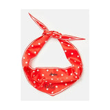 A vibrant red silk joules neckerchief with white polka dots and delicate hello script tied in a stylish knot