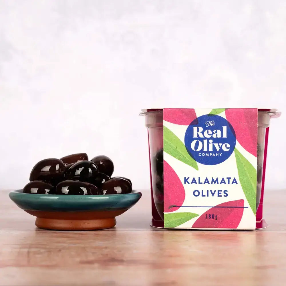 A vibrant pink and green leaf patterned 180g container of the real olive company kalamata whole olives with delphi stuffed green style