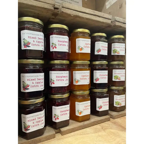 Rows of colorful glass jars of kay’s homemade jams from north devon with gold lids and fruit-labeled tags including quince jelly