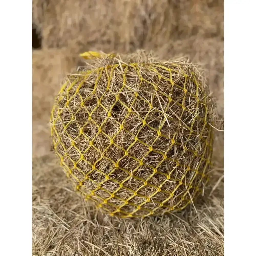 A round hay ball in a bright yellow extra strong polyethylene elite deluxe haynet for durable feeding
