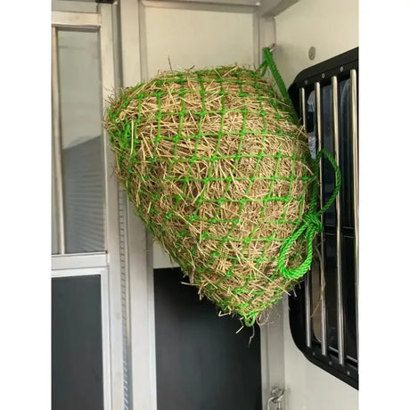 Green mesh km elite travel pony haynet filled with golden straw hanging inside vehicle deluxe travel haynet