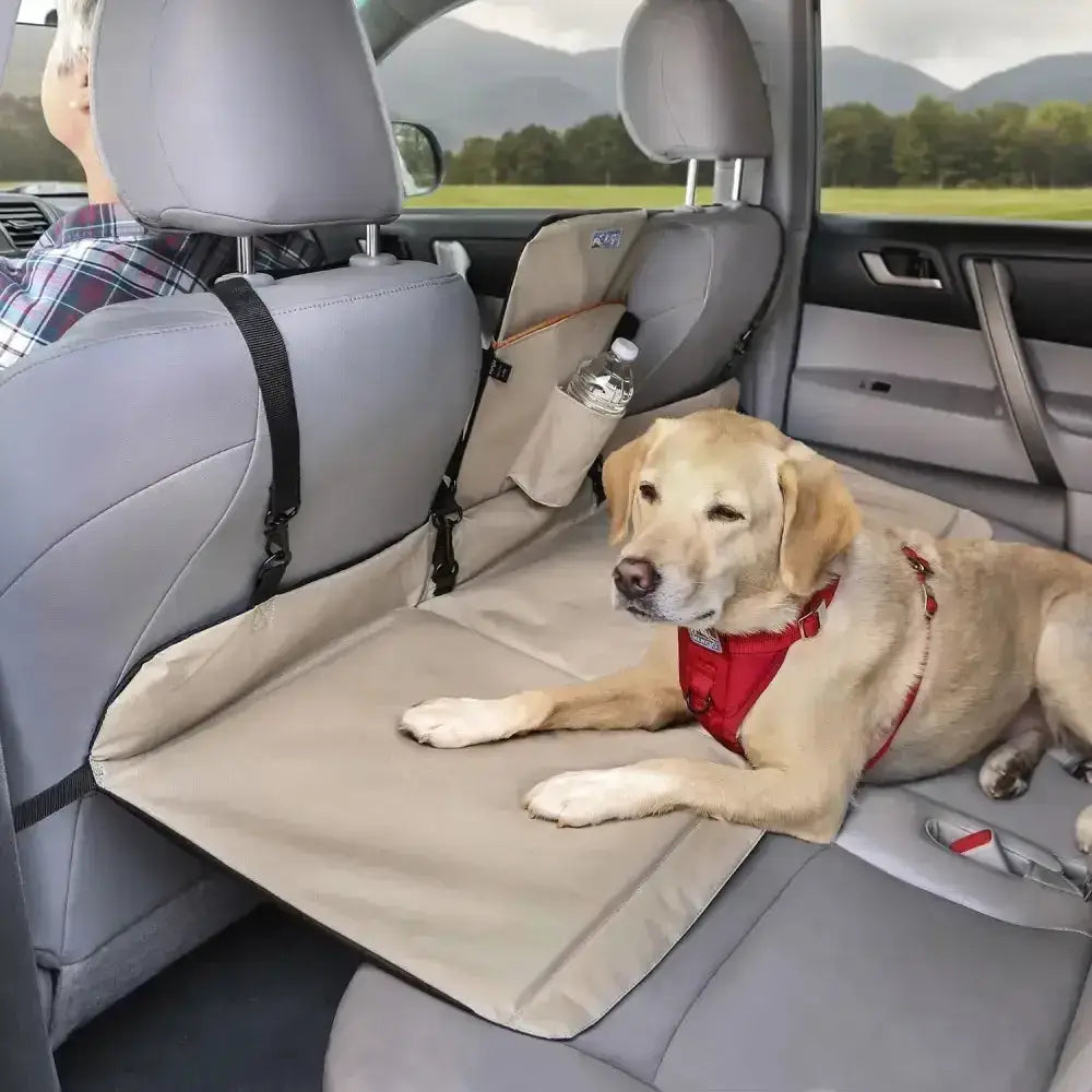 Beige kurgo backseat bridge pet car seat protector with black straps and side pocket holding water bottle