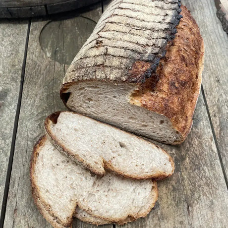 Large brown sliced sourdough with dark cracked crust and soft airy interior slow proofed for 24 hours white bread