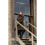 Woman wearing a dark green Lemieux Anya Waterproof Riding Coat Alpine on wooden stairs