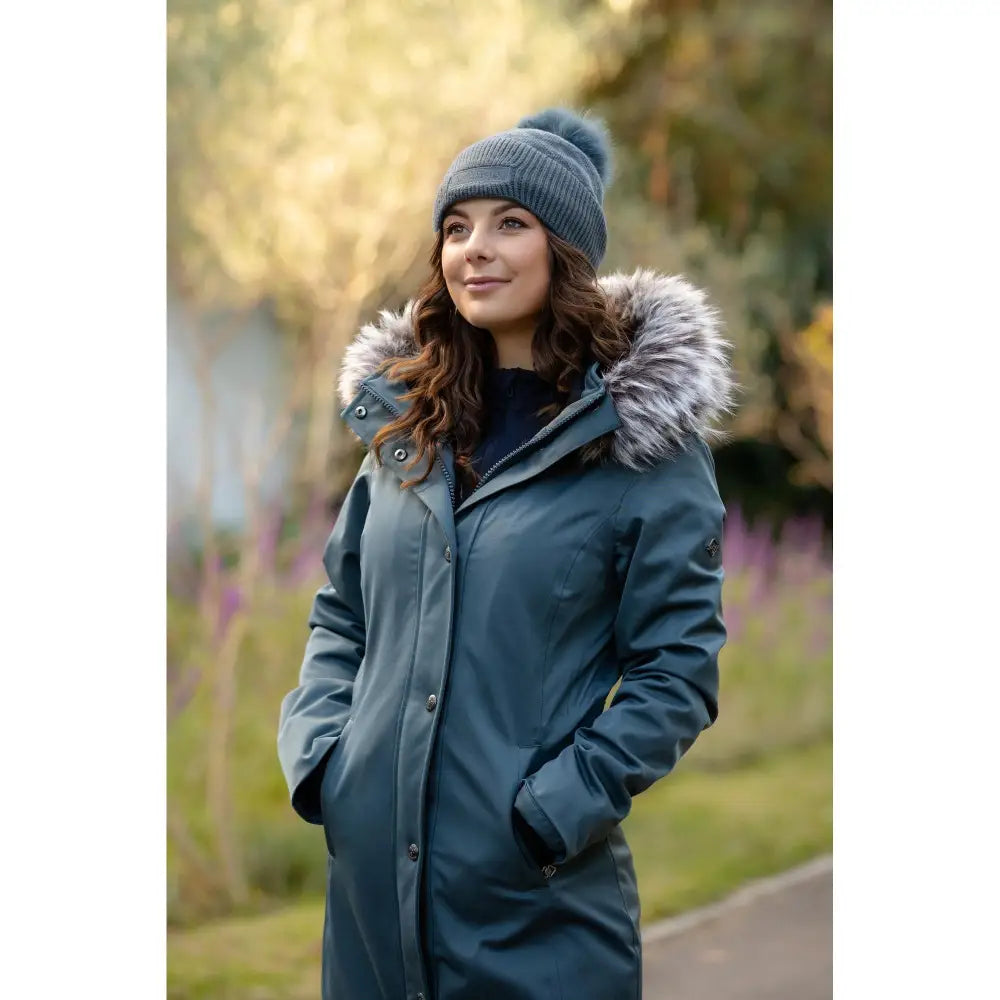 Woman in a blue Lemieux Anya Waterproof Riding Coat Petrol with fur-trimmed hood