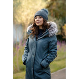 Woman in a blue Lemieux Anya Waterproof Riding Coat Petrol with fur-trimmed hood