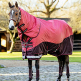 A vibrant pink and maroon lemieux arika ripstop turnout rug cranberry with black straps and anti-static shoulder lining