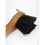 A lemieux artisan hoof pick with a sturdy wooden handle and dense black bristles for removing packed mud