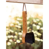 A lemieux artisan hoof pick with a wooden handle and black bristles for removing packed mud easily