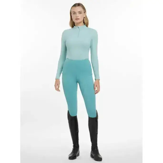 A sleek long-sleeved teal lemieux base layer aqua with high collar and zipper detail for riding comfort