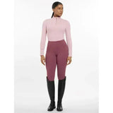 The lemieux base layer blossom features a soft pink long sleeve quarter zip top paired with maroon riding pants and black boots