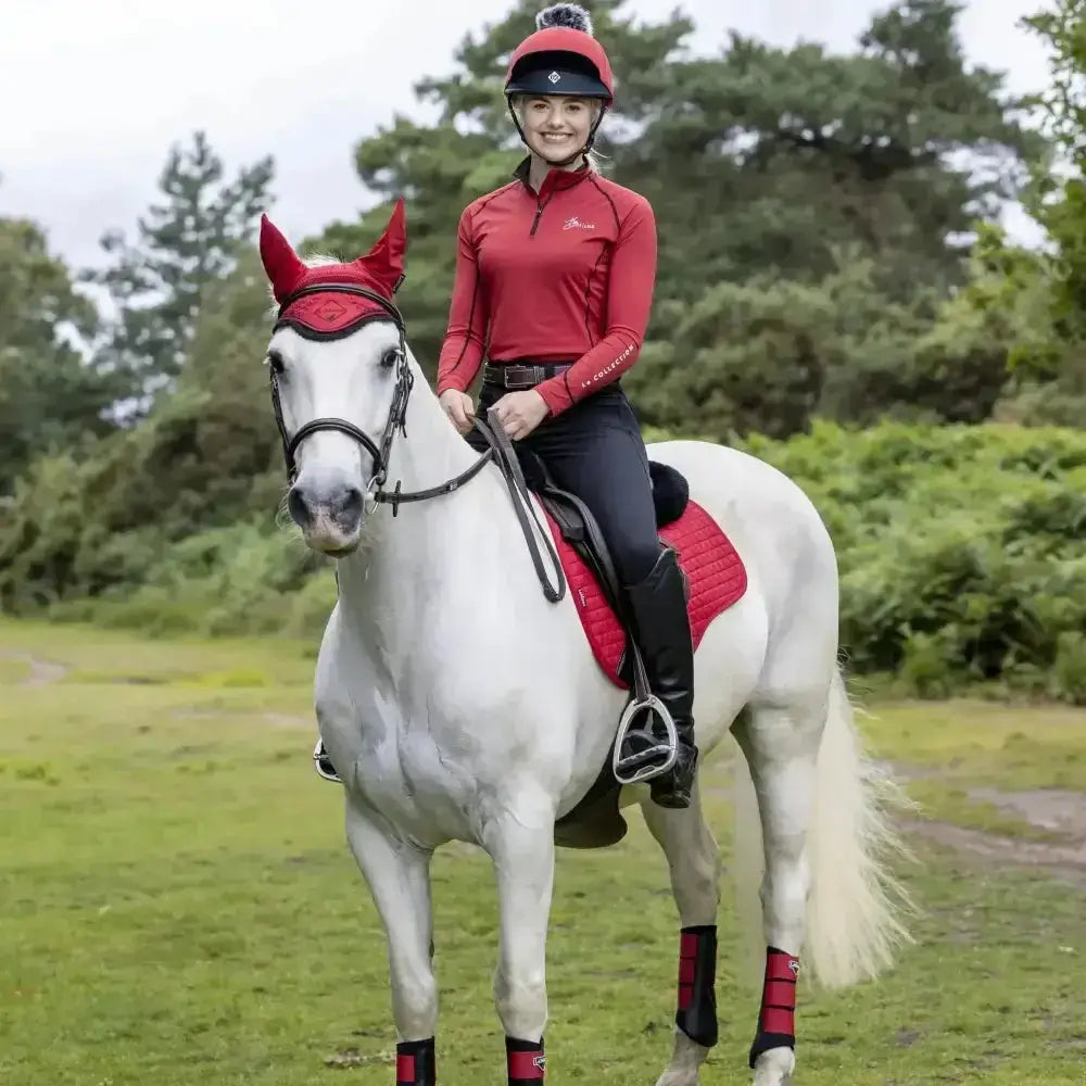 White horse wearing lemieux base layers chilli red protective gear and saddle pad for rider base comfort and style
