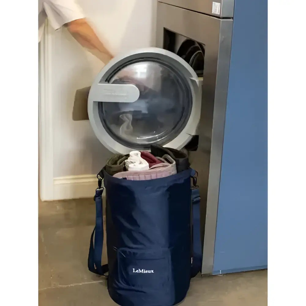 Blue lemieux carry all backpack navy laundry bag with front pocket and shoulder strap next to open washing machine equestrian use