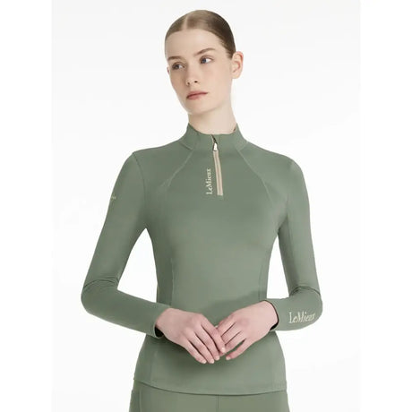 A sage green lemieux classique base long sleeve performance top with high collar zipper and embroidered logo