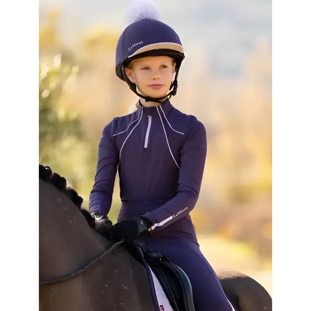 Navy blue lemieux classique pom equestrian helmet with white trim and fluffy white pom hat silk juniper on top