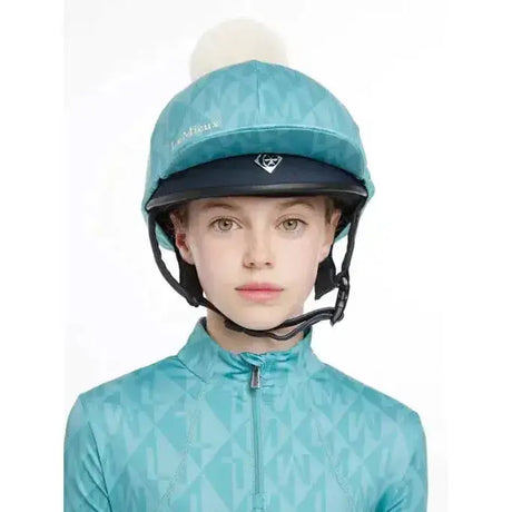Teal patterned lemieux clea hat silk lagoon equestrian helmet with white pom pom and black chin strap