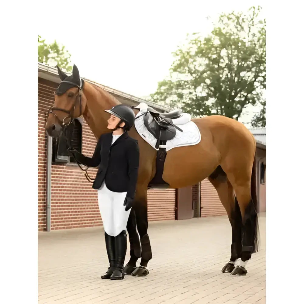 A brown horse wearing a lemieux crystal fly black fly hood standing beside a rider in equestrian gear