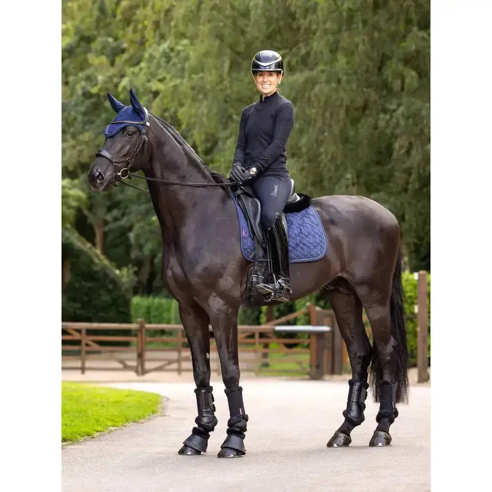 Black horse wearing navy lemieux crystal suede dressage pad with quilted texture and protective leg guards
