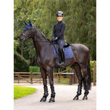 Black horse wearing navy lemieux crystal suede dressage pad with quilted texture and protective leg guards