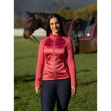 A woman wearing a vibrant coral lemieux dynamique jacket cranberry with quilted zip-up design and high collar