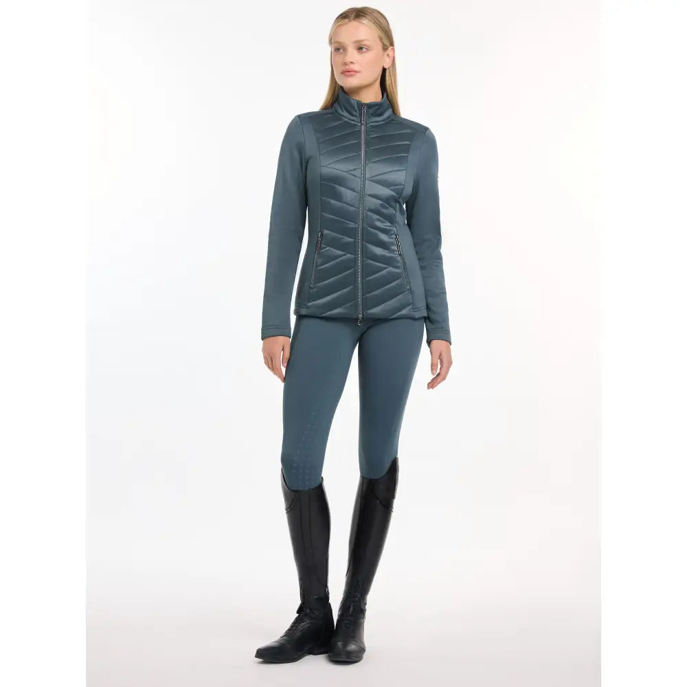 Woman in teal Lemieux Dynamique Jacket Petrol and matching leggings with black riding boots