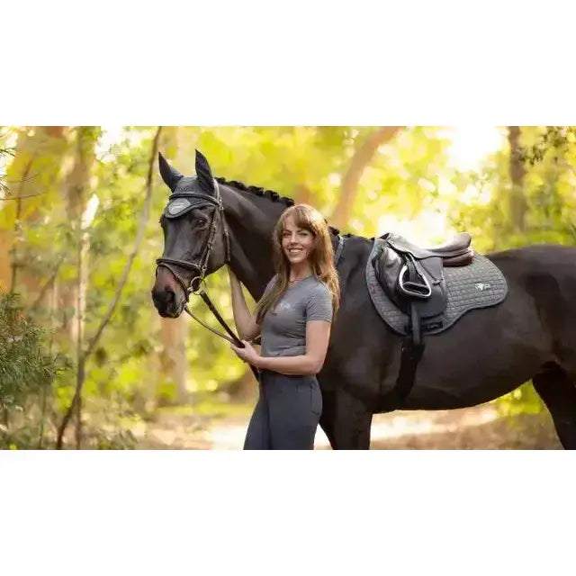 Black horse wearing a lemieux earth gp square moss purpose saddle pad under a sleek dark gray saddle