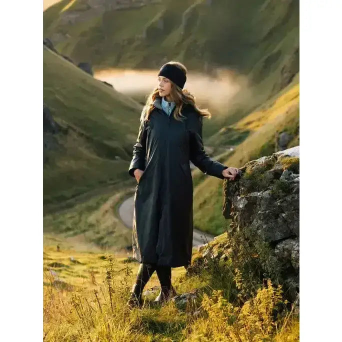 A woman wearing a lemieux elements coat navy full-length waterproof with welded seams and subtle stitching details