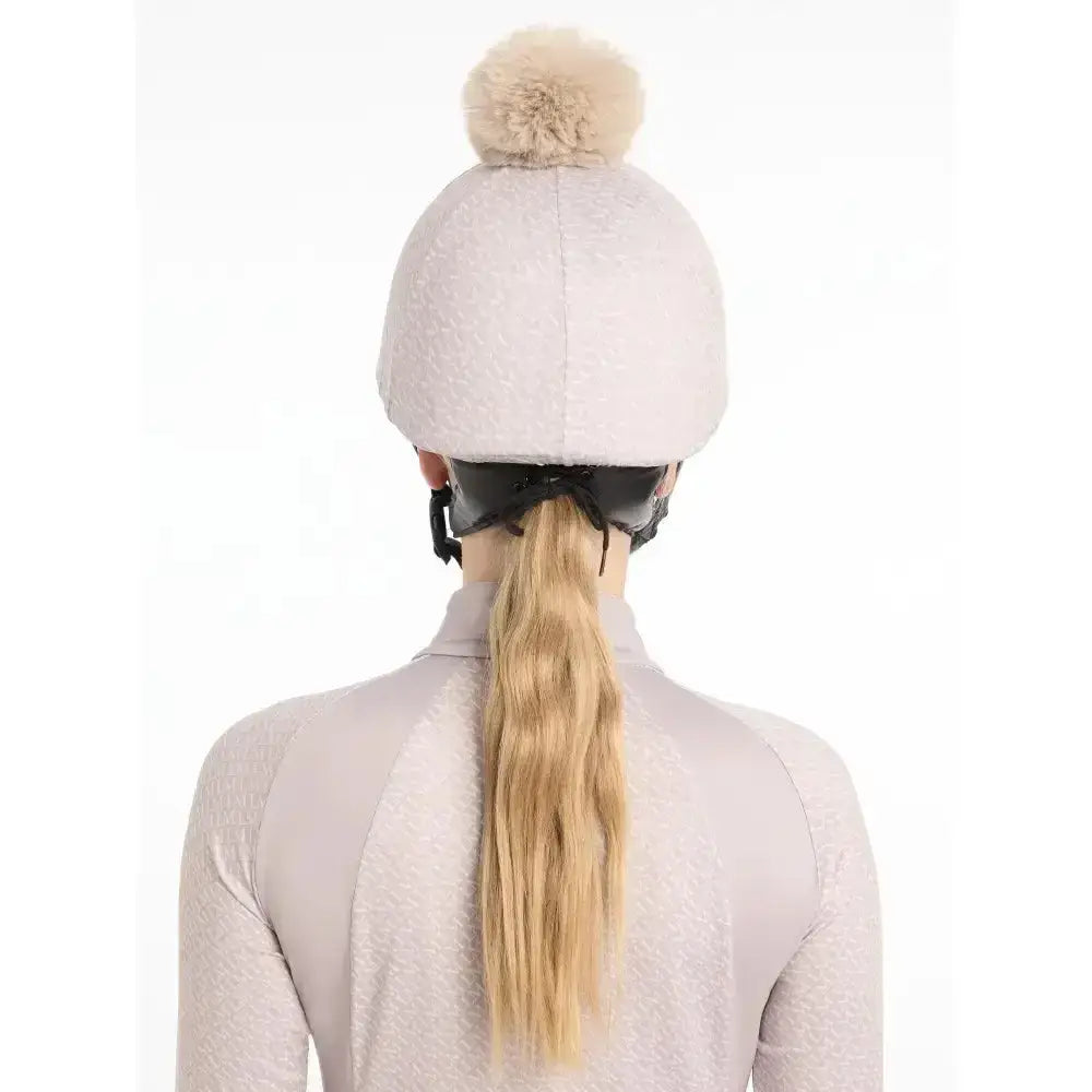 A soft light gray lemieux faith hat with a fluffy beige pom-pom made from faith hat silk material