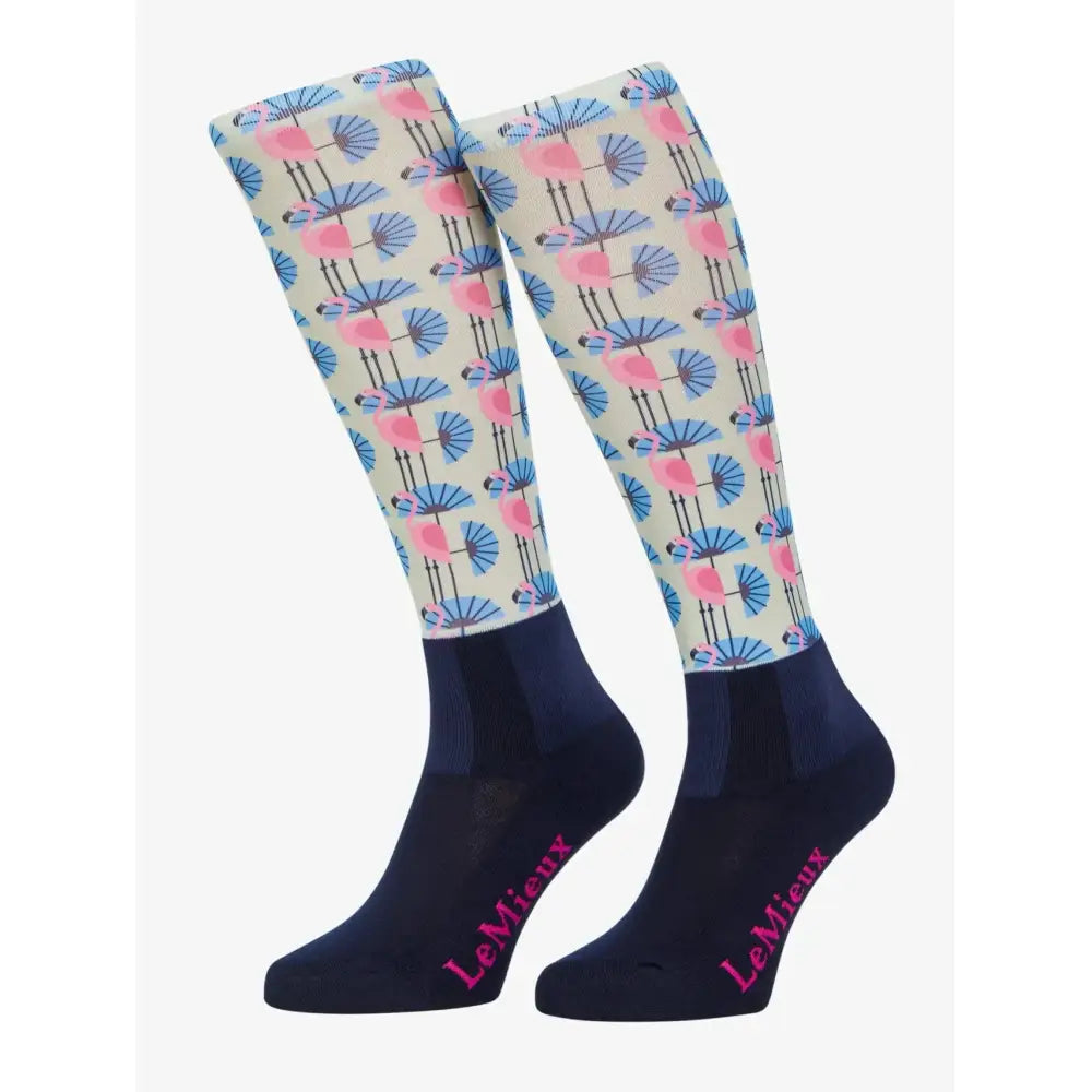 A pair of lemieux footsie socks flamingo with pink flamingos holding blue fans on cream with navy cuffs and toes