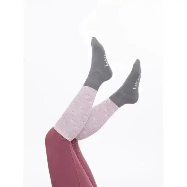 A pair of lemieux footsie socks lemon in two-tone gray and pinkish gray with lambs & ivy logo and speckled texture