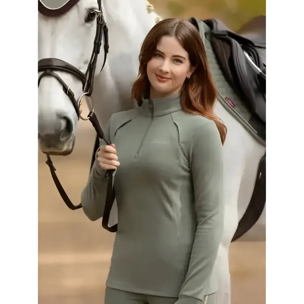 A woman wearing a sage green lemieux frances quarter zip fleece rosemary with long sleeves and subtle seam detailing