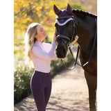 A black horse wearing a purple and white decorative head covering featuring lemieux halle lightweight base layer lilac design