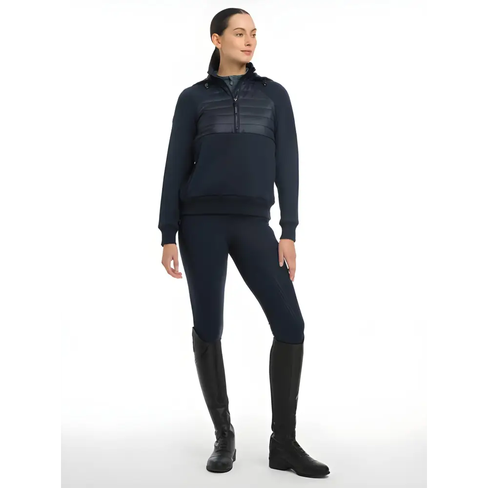 Woman in a dark blue Lemieux Harley Hybrid Hoodie with riding boots for athletic wear