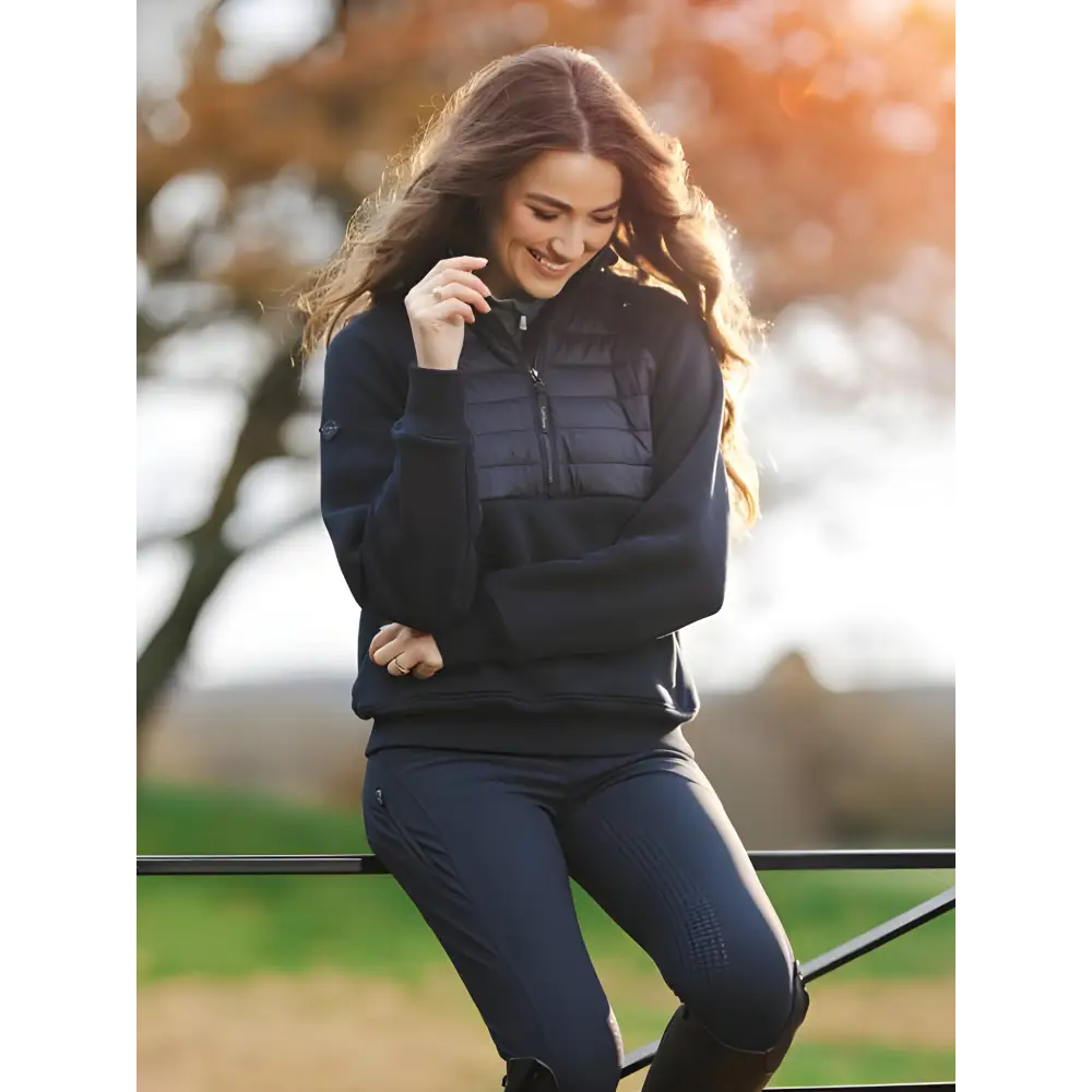 Woman in dark puffer jacket and jeans smiling, featuring Lemieux Harley Hybrid Hoodie Navy