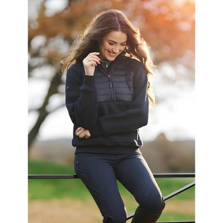 Woman in dark puffer jacket and jeans smiling, featuring Lemieux Harley Hybrid Hoodie Navy