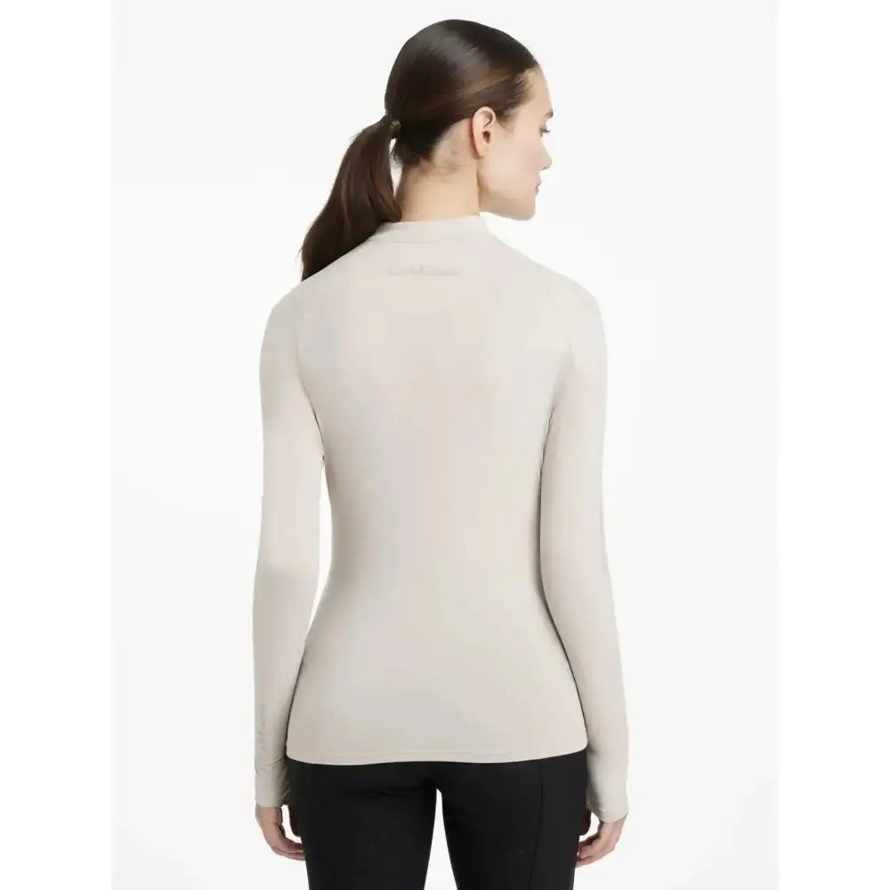 A sleek off-white lemieux heyden lightweight turtleneck base layer stone with smooth form-fitting knit texture