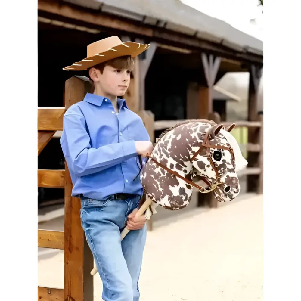 A child holds a brown and white spotted lemieux hobby horse montana with leather straps for playtime fun
