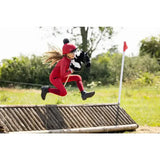 A child in a red equestrian outfit jumps over an obstacle holding a black and white lemieux hobby horse razzle toy