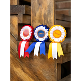 Three colorful Lemieux Hobby Horse Rosette ribbons in red, blue, and yellow