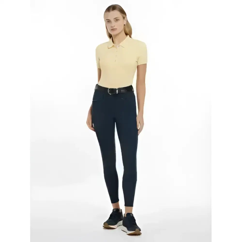 A model wears lemieux imogen knee grip breeches navy with a pale yellow polo shirt and silver buckle belt