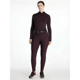 A sleek maroon long sleeve top with high neckline and subtle seams paired with lemieux isabelle seat breeches for equestrian use