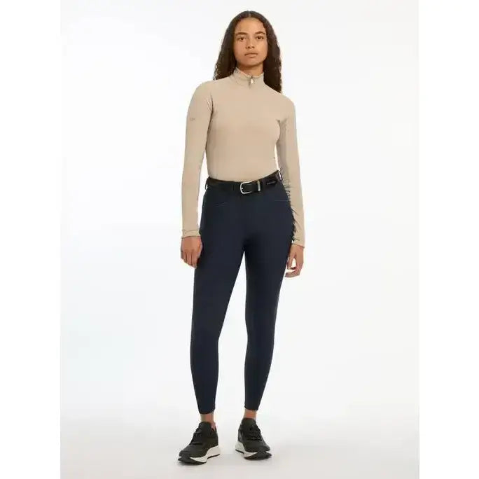 Beige high neck long sleeve riding top with subtle side panel detailing paired with lemieux isabelle seat breeches navy featuring tonal reflective details