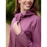 A woman wearing a lemieux isla short waterproof jacket rosewood in purple with adjustable cuffs and hood