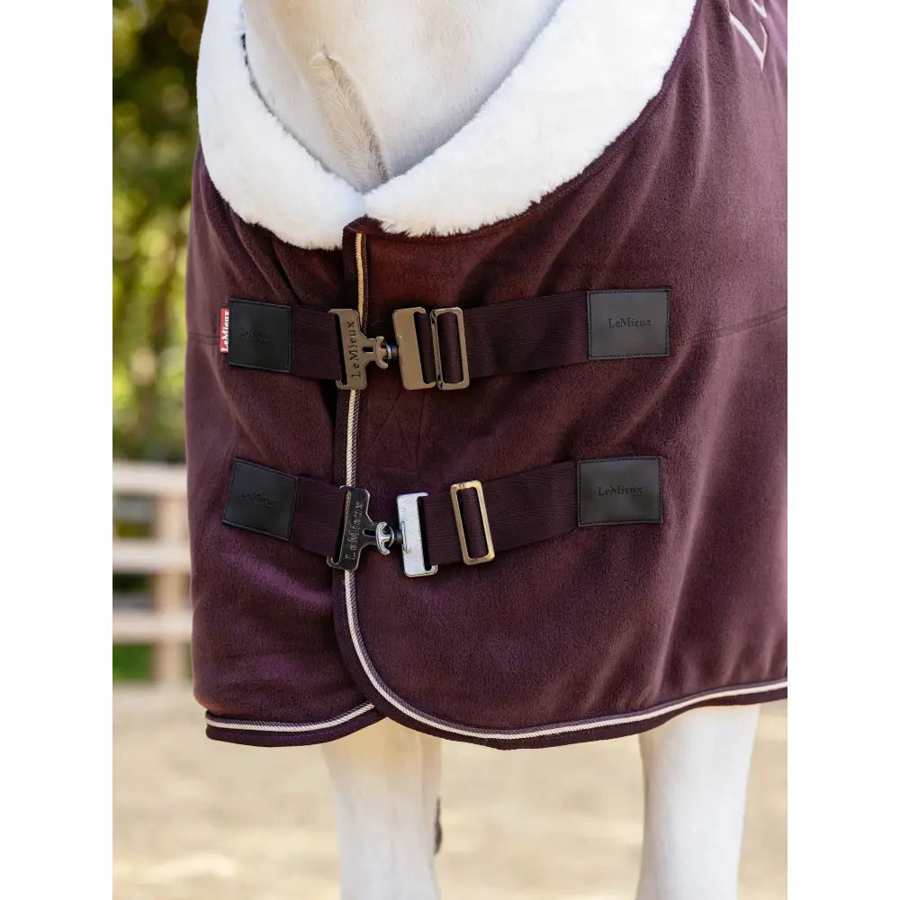 A lemieux kudos luxe fleece rug damson in maroon with a white faux-fur collar and black adjustable straps with silver buckles